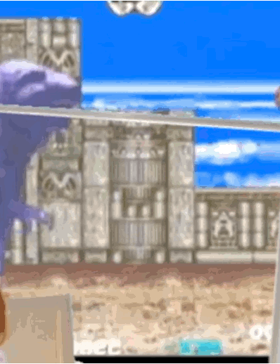 A normal-sized panel. The cat is in a lawn-chair watching a game of the 1992 arcade fighter 'Dino Rex'. Hover-image is a still image of a desk from afar. A computer setup, a water bottle, and an empty can of soda are present. This panel is clickable.